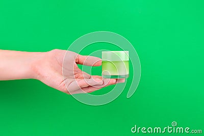 Female hand holding unbranded green plastic tube. Flacon for cream, toiletry. Bottle for professional cosmetics product. Skincare Stock Photo