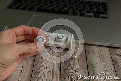 Female hand holding white wireless headphones laptop on Stock Photo