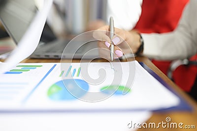 Female hand holds pen over business records with graphs. Stock Photo