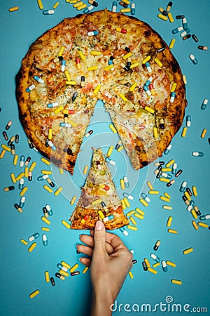 Female Hand Holds In Hand A Piece Of Pizza Sprinkled With Pills, Top view Idea. Biohacking Healthy Food Concept Stock Photo
