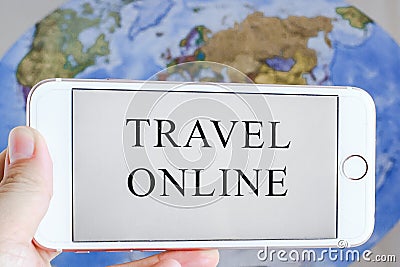 Hand holds a smartphone with the words travel online on a world map background Stock Photo