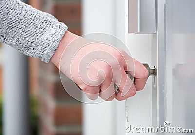 Female hand inserting key in door Stock Photo