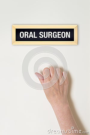 Female hand is knocking on Oral surgeon door Stock Photo