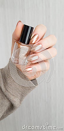 Female hand with pale light long nails and a bottle Stock Photo