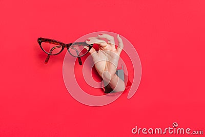 Female hand in paper hole with glasses Stock Photo