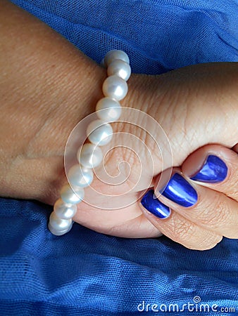 Female hand with pearls bracelet blue background Stock Photo