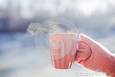 Female hand in pink mittens holding cup with hot tea or coffee. Close up Stock Photo