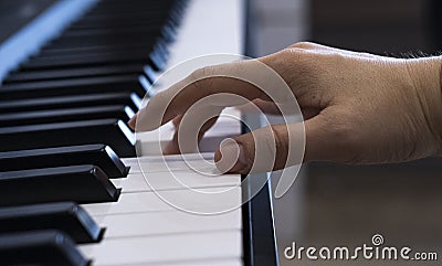 A female hand is playing the electronic digital piano at home. The woman is a professional pianist who arranges music using Stock Photo