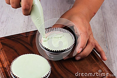 Female Hand Pour Green Cupcake Batter to the Mold with Beatiful Papercup, Baking Process Step by Step in the Kitchen Stock Photo