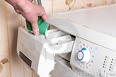 Female hand pour the washing powder detergent into washing machine. Laundry day at home. Stock Photo