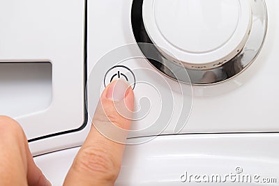 Female hand pushing start stop button of washer, washing machine cycle interraption or starting, beginning Stock Photo