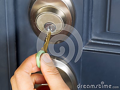 Female hand putting house key into door lock Stock Photo