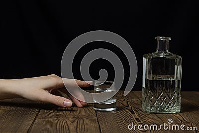 Female hand reaches for a glass with alcohol, black background alcohol Stock Photo