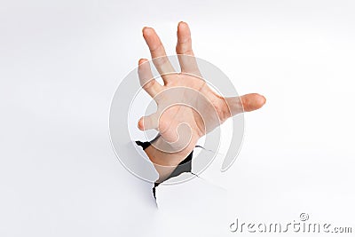 Female hand reaching through torn paper sheet Stock Photo