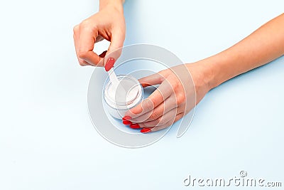 Female hand with red nail polish and unbranded open cream jar . Flacon for cream, toiletry. Bottle for professional cosmetics Stock Photo