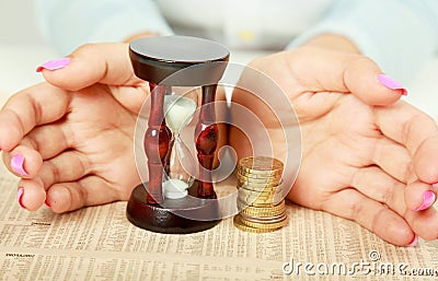 Female hand's with hourglass and coin. Stock Photo