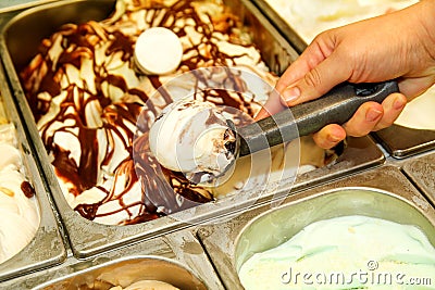 Female hand with scoop takes ice cream from the fridge and serving in ceramic white cups. Stock Photo