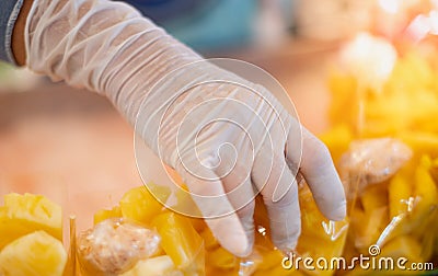 Female hand seller wearing surgical glove and selling the fresh pineapple for hygience to buyer at the local market Stock Photo