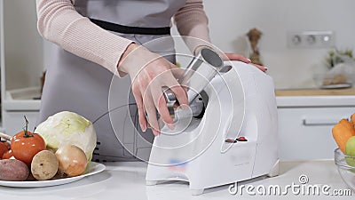 Female hand sets stainless steel head in meat grinder for providing quality mince from meat. Electric mincer machine for Stock Photo