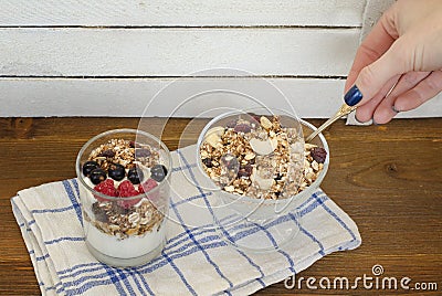 Female hand with spoon, yogurt and granola. Traditional American Stock Photo