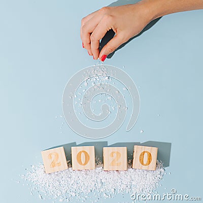 Female hand sprinkling snow imitation on 2020 number laid out with toy cubes Stock Photo