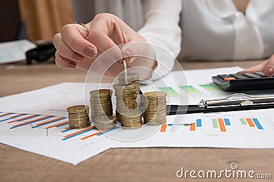 Female hand stacking euro coins into columns above business diagram Stock Photo