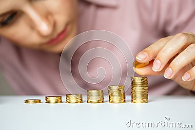 Female hand stacking gold coins into increasing columns Stock Photo