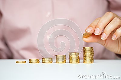 Female hand stacking gold coins into increasing columns Stock Photo