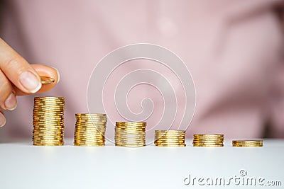 Female hand stacking gold coins into increasing columns Stock Photo