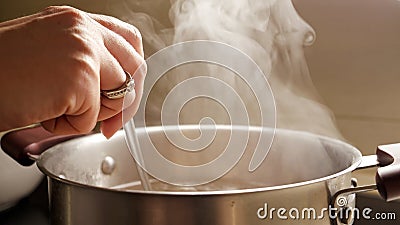 Female hand stirring boiling soup in pot. Healthy nutrition, cooking at home, hot steam Stock Photo