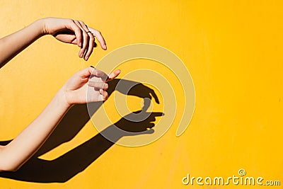Summer girl teen dancing under direct sun light Minimal happines concept, close up hands silhoutte with shandows yellow background Stock Photo