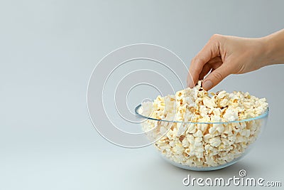 Female hand take popcorn from bowl on light gray background Stock Photo