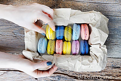 Female hand taking macaron from the package. Stock Photo