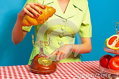 Female hand tasting crispy croissant on plaid tablecloth isolated on bright blue background. Vintage, retro style Stock Photo