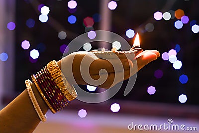 Woman holds lit earthen diwali lamp in one hand Stock Photo