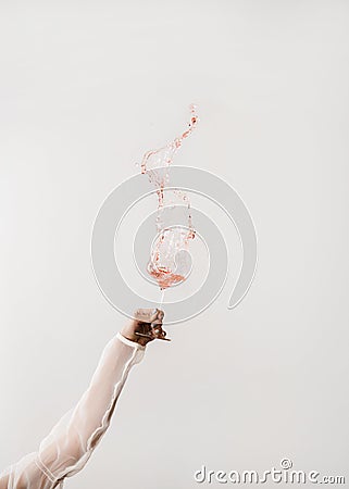 Female hand swirling glass of rose wine making splash Stock Photo