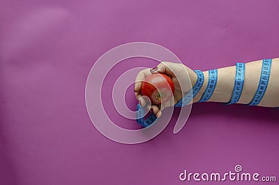 Female hand, wrapped with measuring tape, holds a tomato Stock Photo