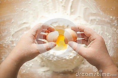 Female hands breaking a chicken egg into flour Stock Photo