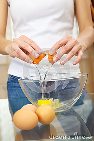 Female hands breaking eggs into a bowl Stock Photo