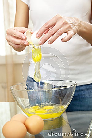 Female hands breaking eggs into a bowl Stock Photo