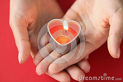 In female hands burning candle in form of heart Stock Photo