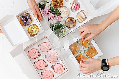 Female hands carefully arranging colorful sweets in white windowed boxes Stock Photo