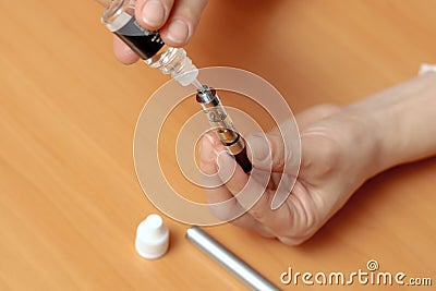 Female hands fill with liquid in the e-cigarette clearomizers Stock Photo