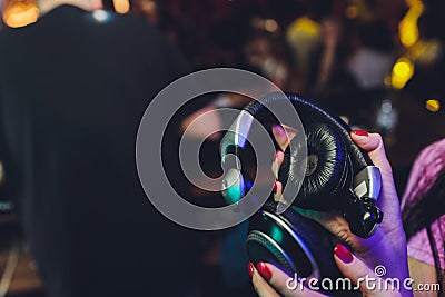 Female hands fold folding stereo headphones on a club background. Stock Photo
