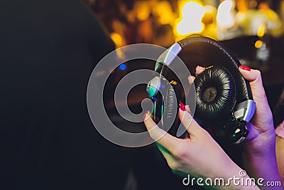 Female hands fold folding stereo headphones on a club background. Stock Photo