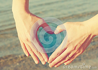 Female hands in the form of heart against the sea. Stock Photo