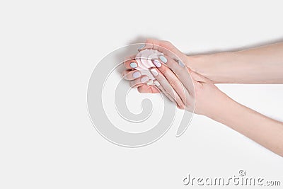 Female hands with a gentle manicure on a white wooden background. Marshmallow in the hands Stock Photo