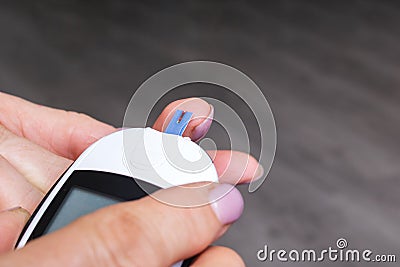 Female hands and glucometer measuring blood sugar Stock Photo