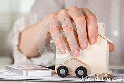 Female hands grasp small wooden house. Stock Photo