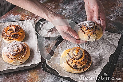 Female hands hold a fresh sweet homemade cinnamon roll with chocolate cream. Scandinavian cuisine. Hyugge style Stock Photo